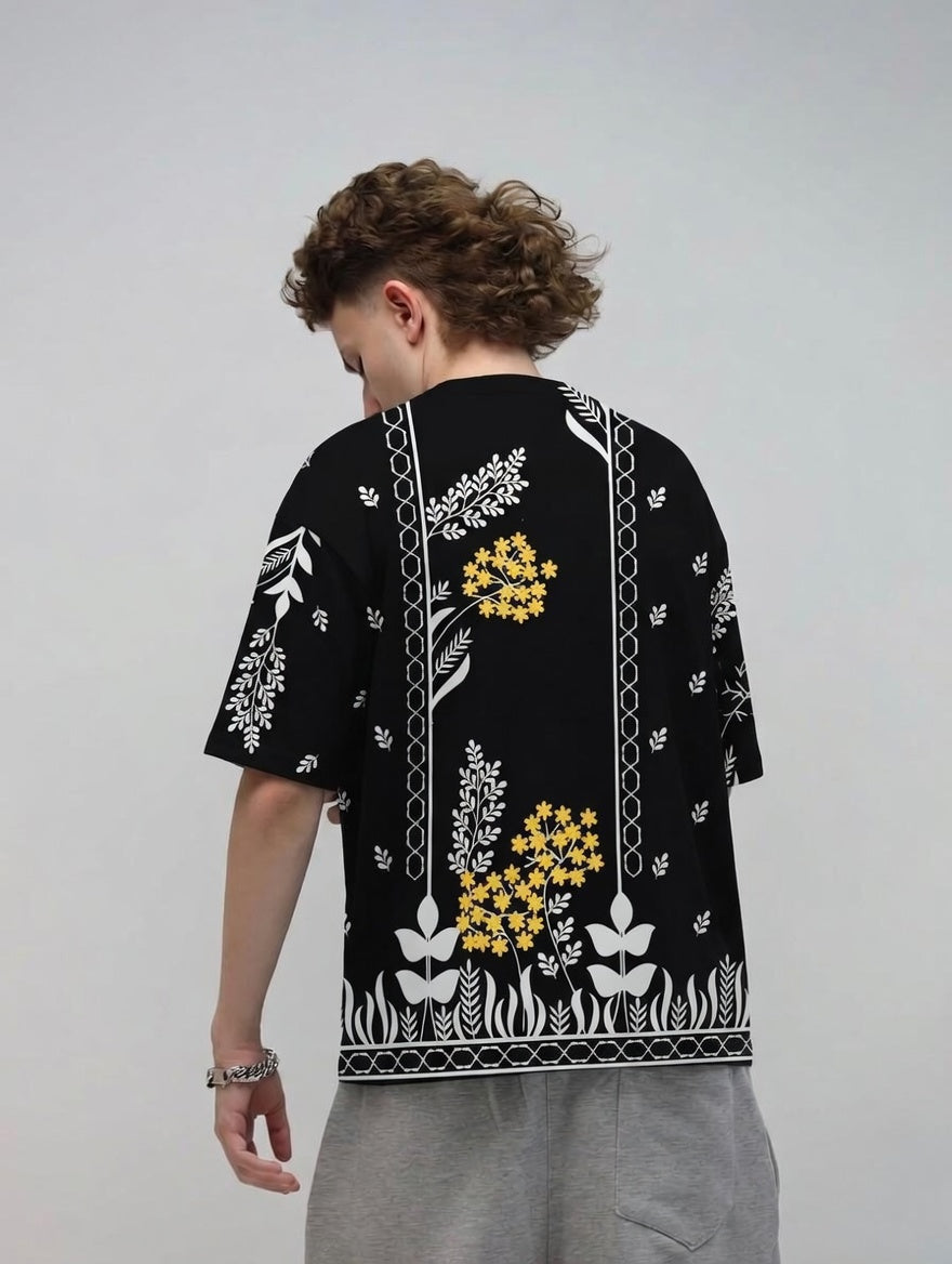 Person wearing a black t-shirt with floral patterns on a plain background