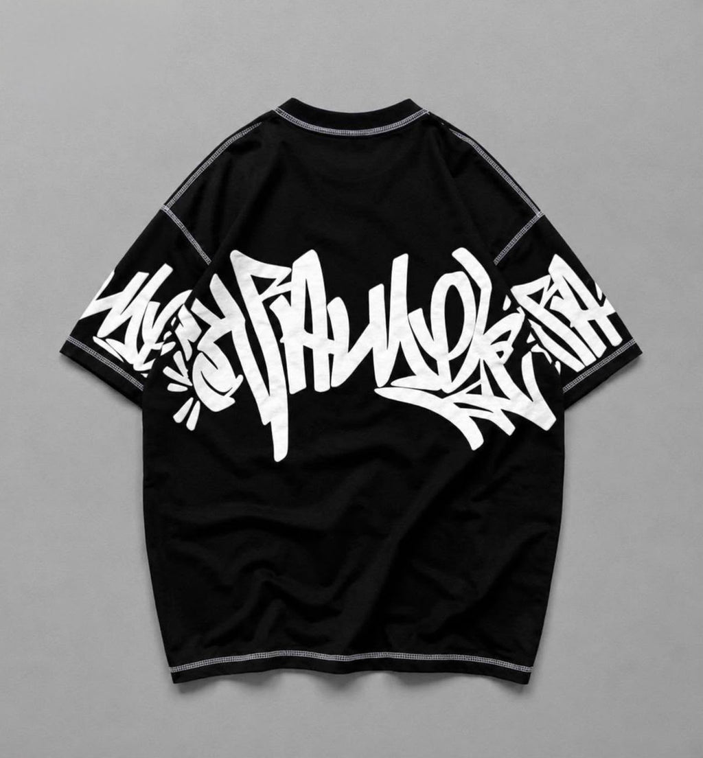 A black short-sleeve t-shirt with a large white graffiti-style graphic printed across the front, displayed flat against a neutral gray background.