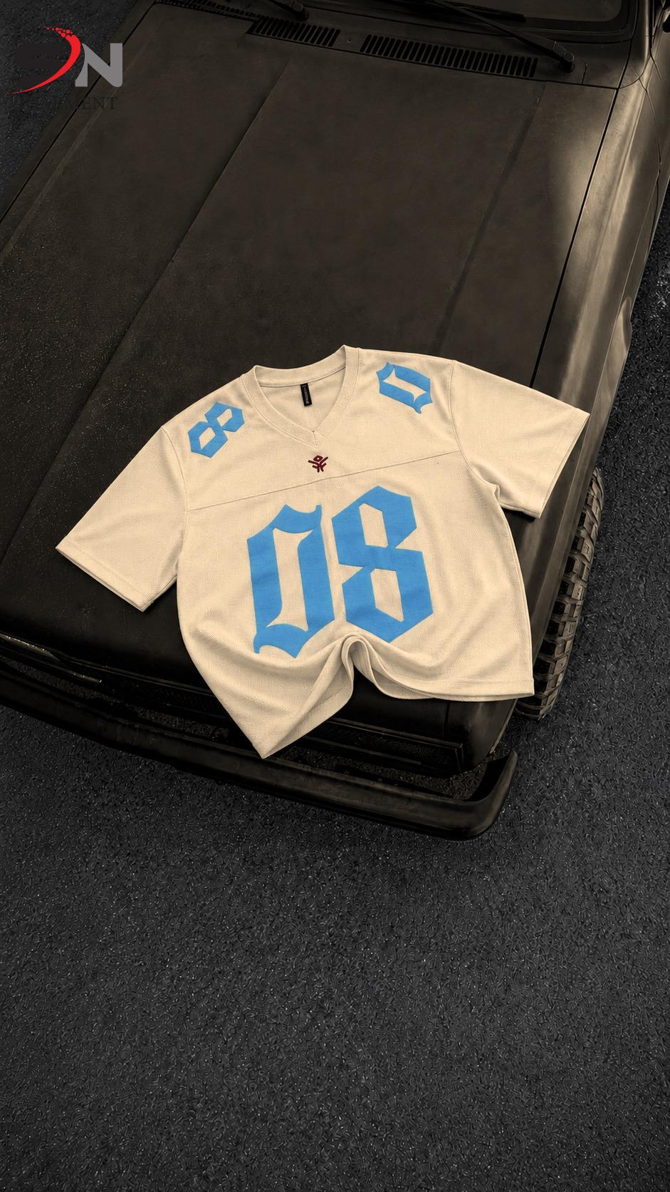 A white short-sleeve athletic jersey with large blue '08' numbers on the front and blue numbers on the shoulders, laid flat on a black vehicle hood over a dark carpeted floor.