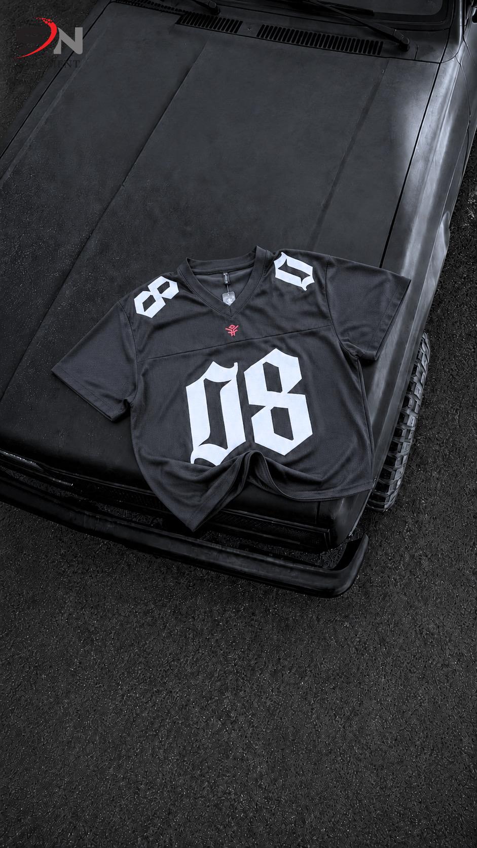 A black short-sleeve football-style jersey with large white '08' numerals on the front and white '8' details on the shoulders, laid flat on the hood of a black vehicle.