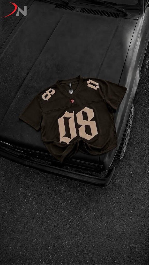 A dark brown football-style jersey with large beige number 08 on the front and beige numbers on the shoulders, laid flat on the hood of a black vehicle.