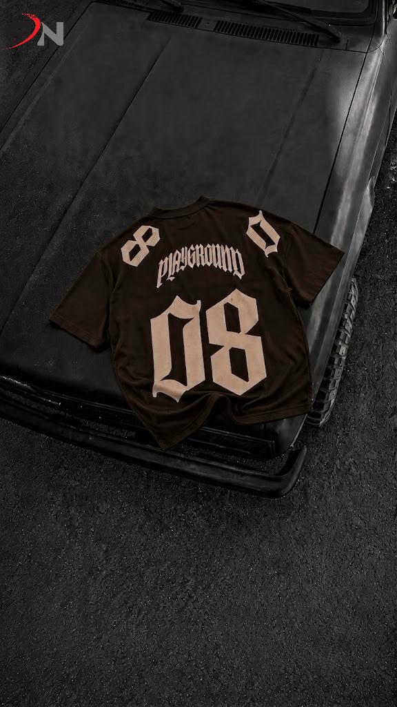 A dark brown t-shirt with 'Pleasantonville' and the number '08' printed on the back, laid flat on the hood of a black car.