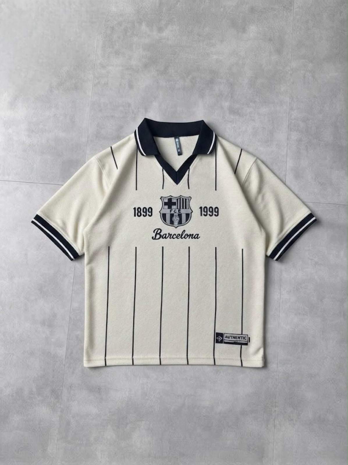 A vintage-style FC Barcelona short-sleeve polo shirt in off-white with navy blue pinstripes and trim, laid flat on a textured gray background.
