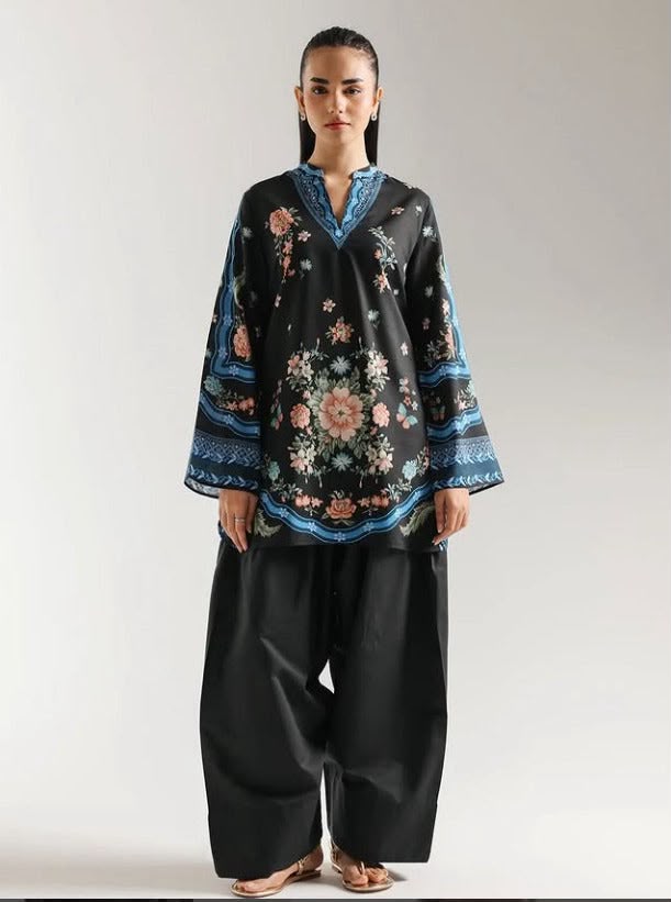 Person wearing a black floral embroidered top and black pants on a white background
