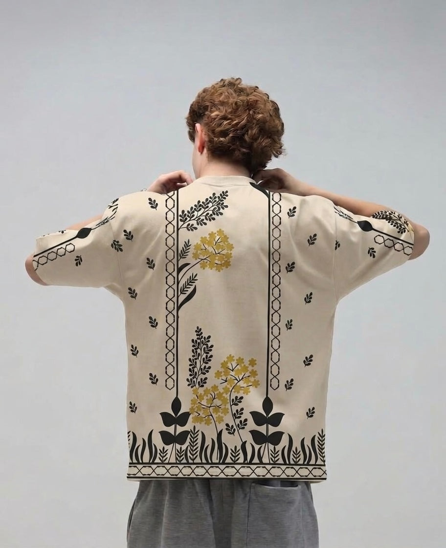 Person wearing a beige shirt with floral embroidery on a plain background