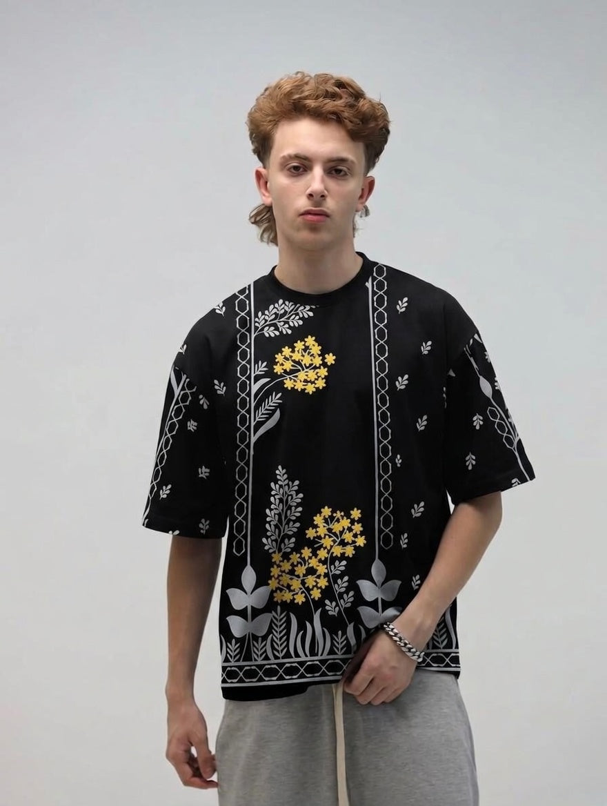 Person wearing a black patterned shirt with yellow floral designs on a plain background